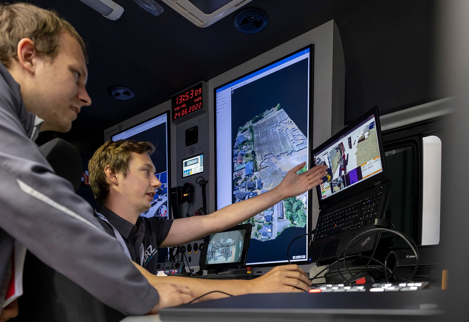 Two men working in a control centre with lots of screens