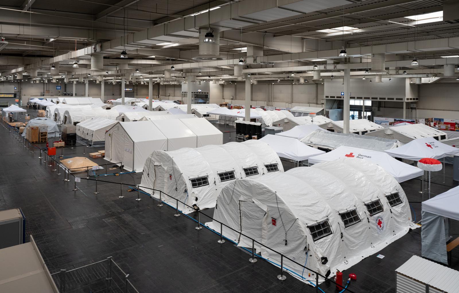 Eine Gesamtansicht zeigt das großflächig aufgebaute Feldkrankenhaus des Deutschen Roten Kreuzes mit zahlreichen Behandlungs- und Versorgungszelten in einer Messehalle.